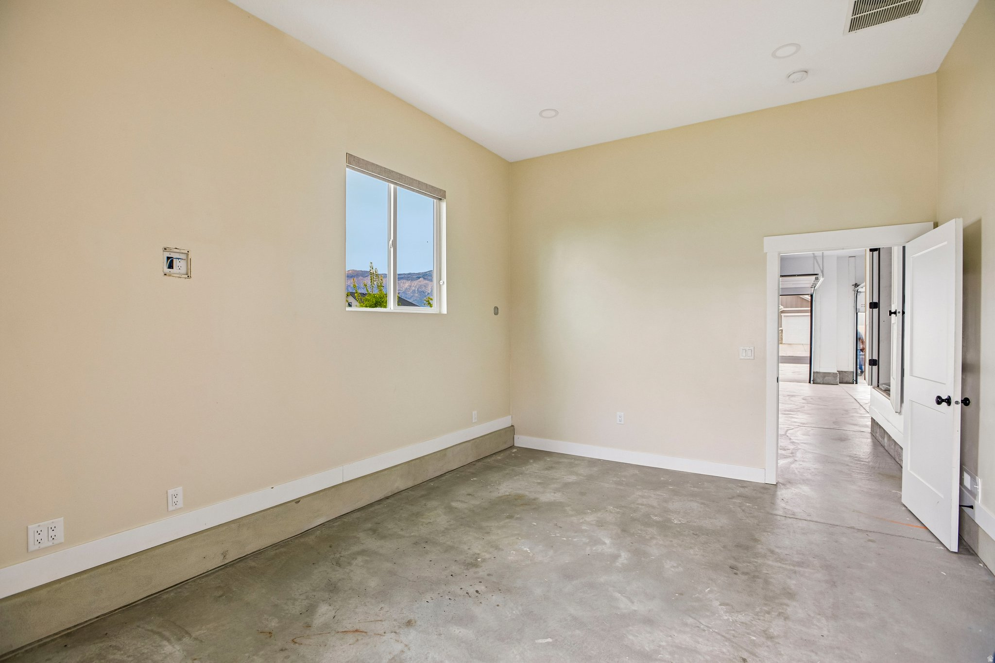 Concrete flooring, high ceilings, recessed lighting, white trim, and a window with a mountain backdrop