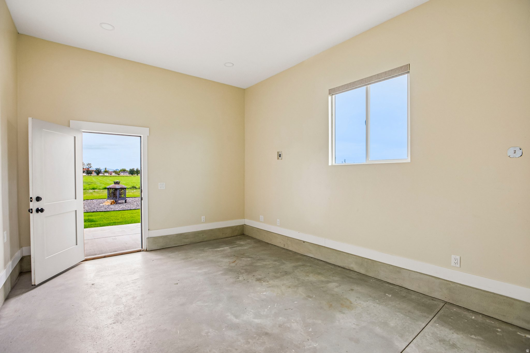 Concrete flooring, white trim, recessed lighting, and an exterior door leading to a patio