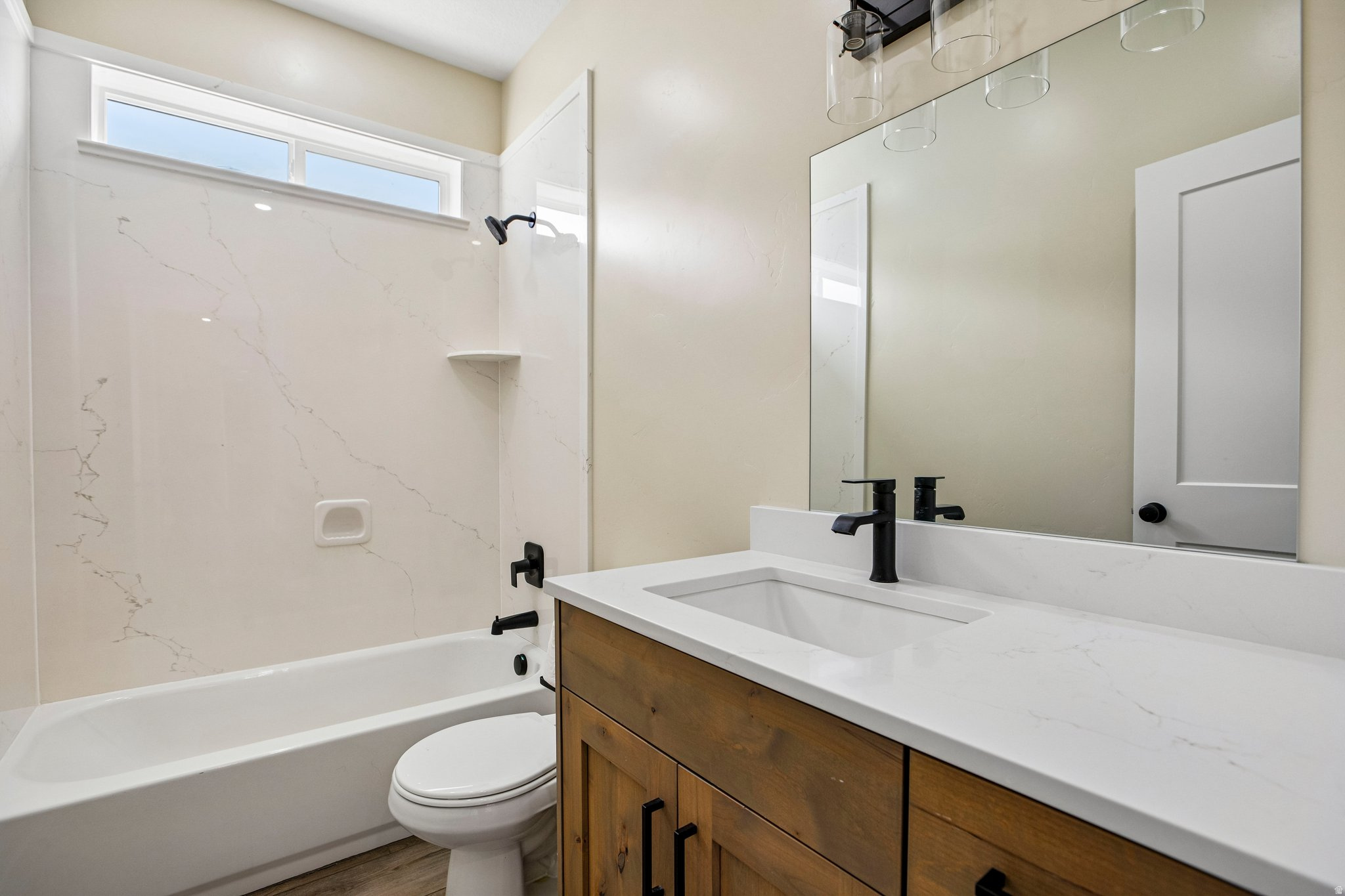 Contemporary bathroom featuring a wood-finish vanity with a white countertop, an integrated rectangular sink, and matte black fixtures