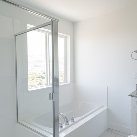 Bathroom featuring vanity, a bathtub, and light tile floors