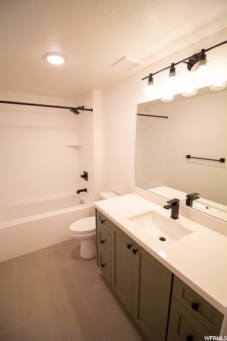 full bathroom with tile floors, washtub / shower combination, oversized vanity, mirror, and toilet