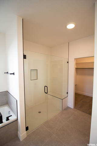bathroom featuring tile flooring and separate shower and tub