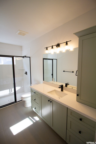 bathroom with shower door, oversized vanity, mirror, and toilet