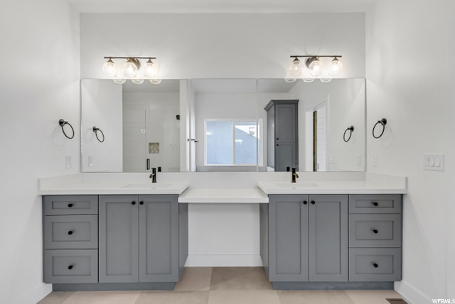 bathroom with tile floors, dual mirrors, and dual vanities