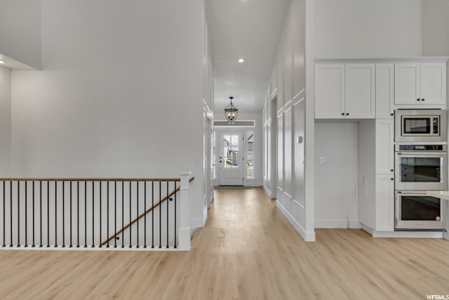 hallway featuring natural light, hardwood floors, and microwave