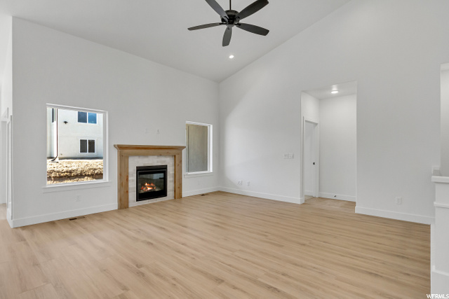 living room featuring hardwood flooring, a fireplace, vaulted ceiling, and a ceiling fan