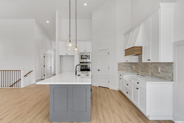kitchen featuring lofted ceiling, a center island, oven, white cabinets, light parquet floors, light countertops, and pendant lighting