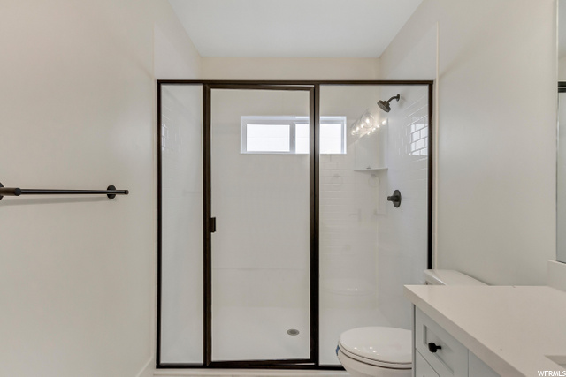 full bathroom with a wealth of natural light, toilet, shower cabin, and vanity