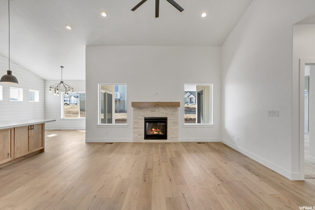 hardwood floored living room featuring natural light, a fireplace, and a ceiling fan