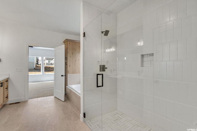 bathroom featuring natural light, tile flooring, vanity, and shower with separate bathtub