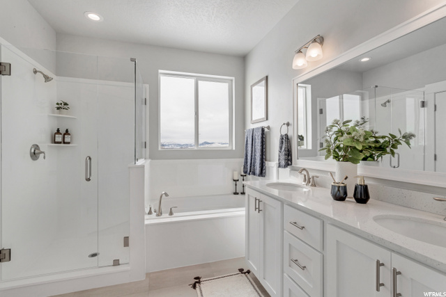 bathroom with natural light, tile floors, separate shower and tub, mirror, and double vanity