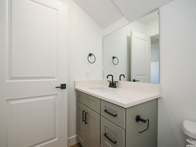 half bathroom with mirror, vanity, and toilet
