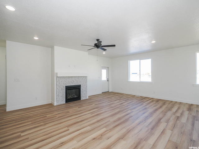 hardwood floored living room featuring a fireplace, natural light, and a ceiling fan