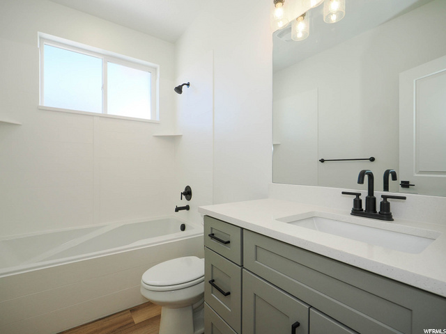 full bathroom with natural light, shower / washtub combination, mirror, vanity, and toilet