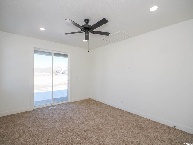 carpeted empty room with natural light and a ceiling fan
