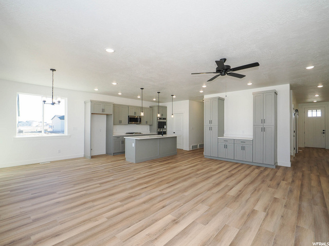 kitchen featuring a ceiling fan, microwave, light parquet floors, light countertops, and pendant lighting