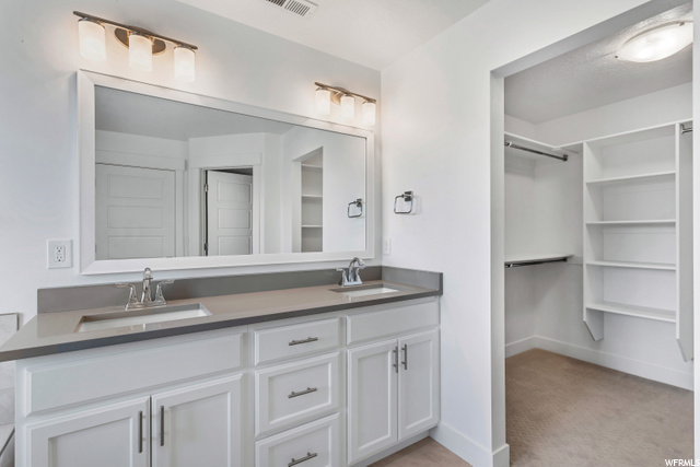 bathroom with his and her sinks, dual large vanities, and mirror