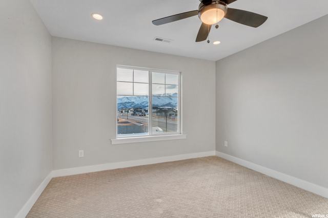 spare room with carpet, a ceiling fan, and natural light