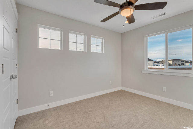 carpeted spare room with a ceiling fan and natural light