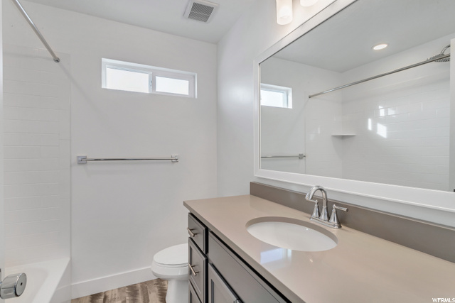 full bathroom with a healthy amount of sunlight, toilet, mirror, shower / bath combination, and large vanity