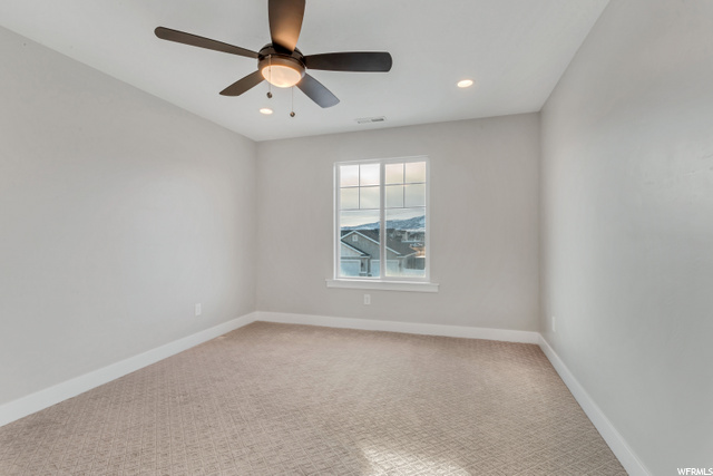empty room with carpet, a ceiling fan, and natural light
