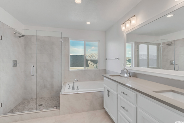 bathroom featuring natural light, tile floors, dual bowl vanity, independent shower and bath, and mirror