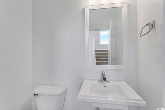 half bathroom with toilet, sink, and mirror