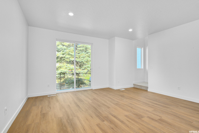 wood floored spare room featuring a healthy amount of sunlight