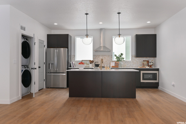 kitchen with separate washer and dryer, refrigerator, extractor fan, light countertops, pendant lighting, dark brown cabinets, and light hardwood flooring