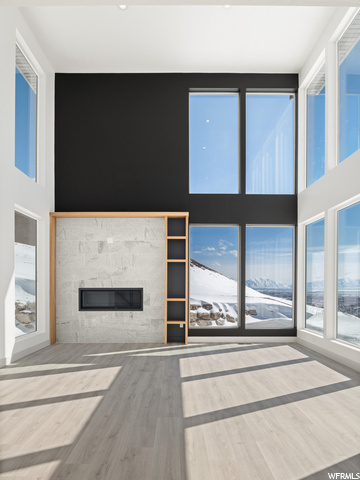 hardwood floored living room featuring a high ceiling, natural light, and a fireplace