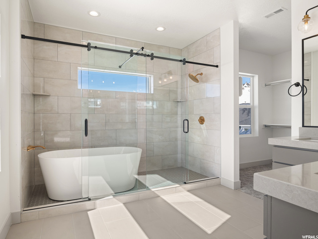 bathroom with tile flooring, separate shower and tub enclosures, and vanity