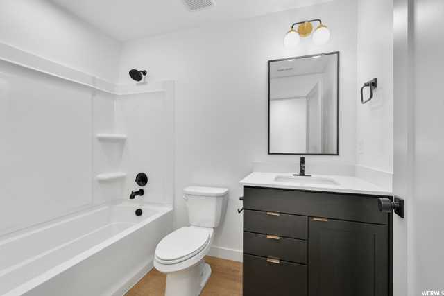 full bathroom with wood-type flooring, shower / bathtub combination, toilet, vanity, and mirror