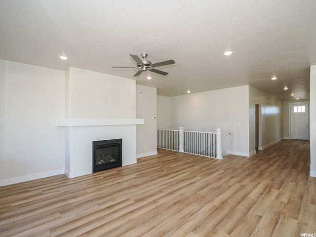 hardwood floored living room featuring a ceiling fan and a fireplace