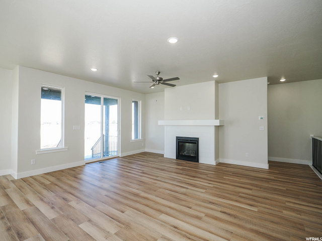 hardwood floored living room featuring natural light, a ceiling fan, and a fireplace