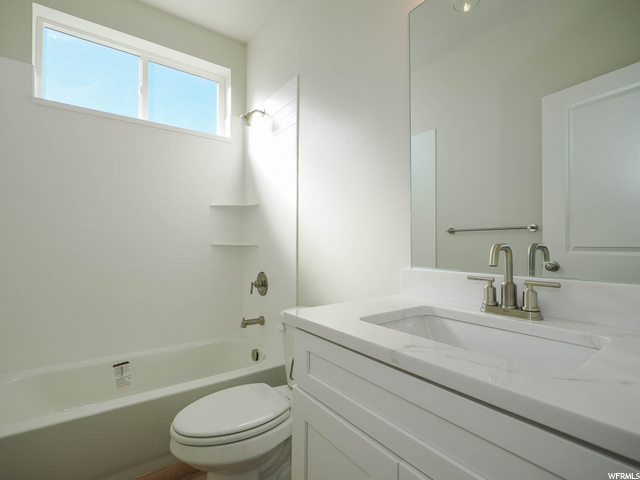 full bathroom featuring natural light, shower / washtub combination, mirror, vanity with extensive cabinet space, and toilet