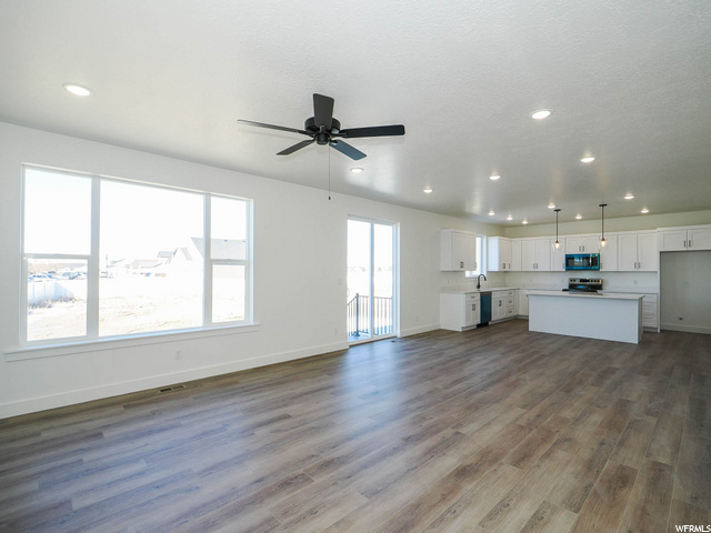 hardwood floored living room featuring natural light, a ceiling fan, and microwave