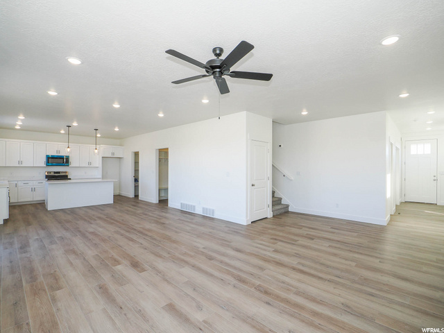 hardwood floored living room featuring a ceiling fan and microwave