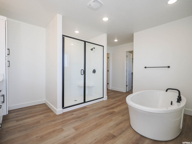 bathroom with hardwood floors, vanity, and independent shower and bath