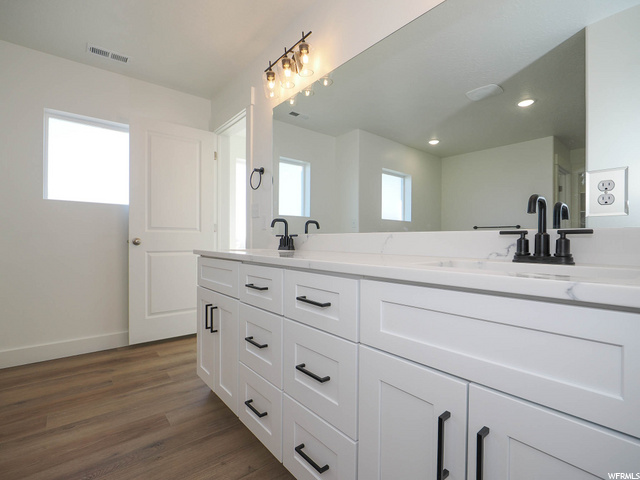 bathroom with hardwood floors, plenty of natural light, mirror, and double sink vanity