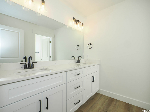 bathroom featuring hardwood flooring, mirror, and double large sink vanity