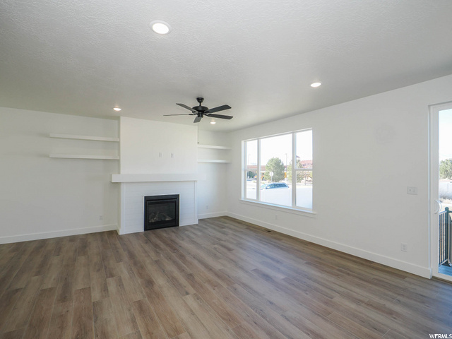 hardwood floored living room with a fireplace, natural light, and a ceiling fan