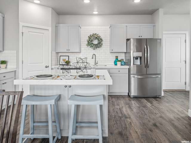 kitchen featuring a breakfast bar, refrigerator, light countertops, and white cabinets