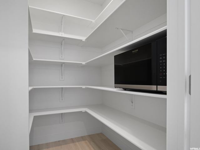 pantry with hardwood floors and microwave