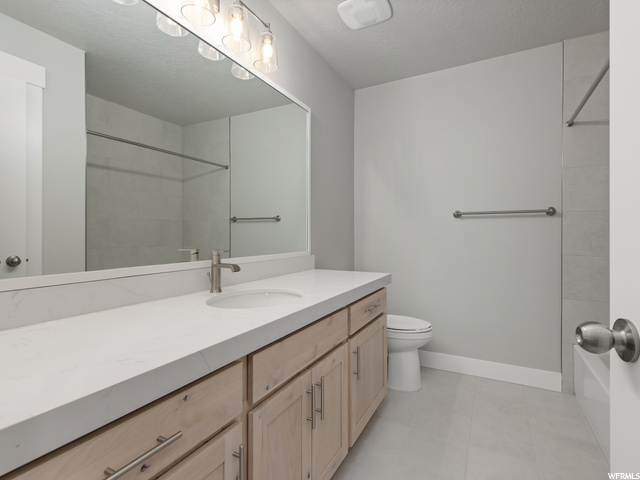 half bathroom featuring tile flooring, toilet, vanity, and mirror