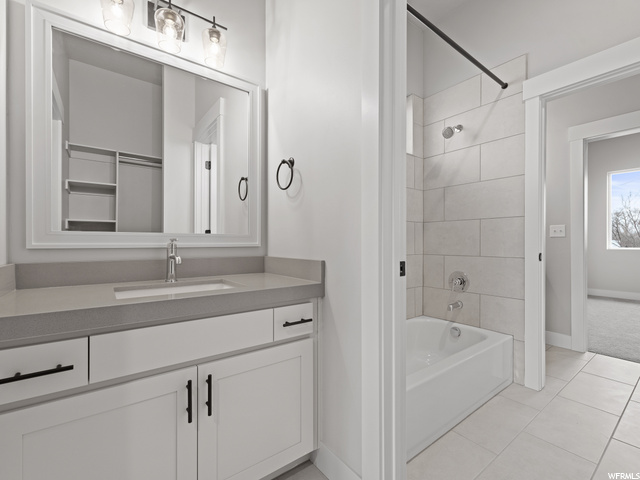 bathroom featuring tile floors, shower / bathtub combination, vanity, and mirror