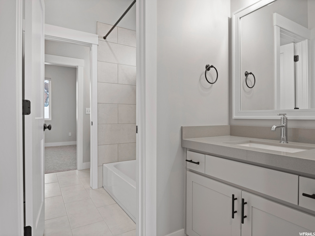 bathroom featuring tile floors, mirror, oversized vanity, and shower / bathtub combination