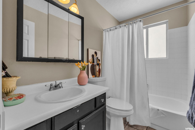 full bathroom with natural light, tile floors, toilet, shower curtain, bathing tub / shower combination, mirror, and oversized vanity
