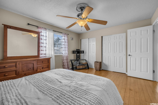 bedroom with wood-type flooring, a ceiling fan, and natural light