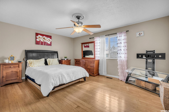 hardwood floored bedroom featuring natural light and a ceiling fan