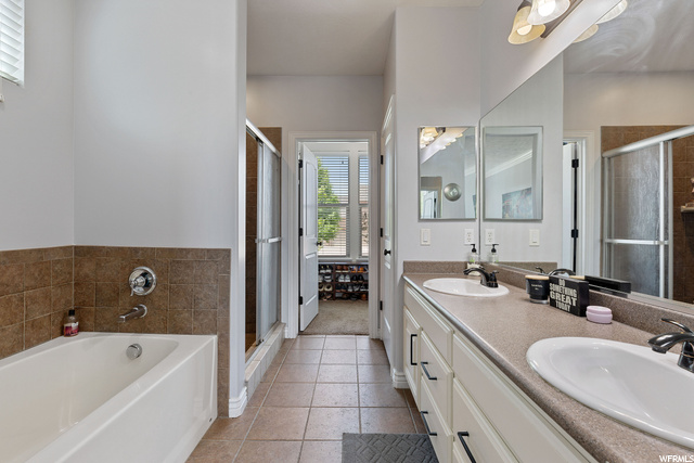 Bathroom featuring tile flooring, natural light, separate shower and tub, mirror, and dual bowl vanity